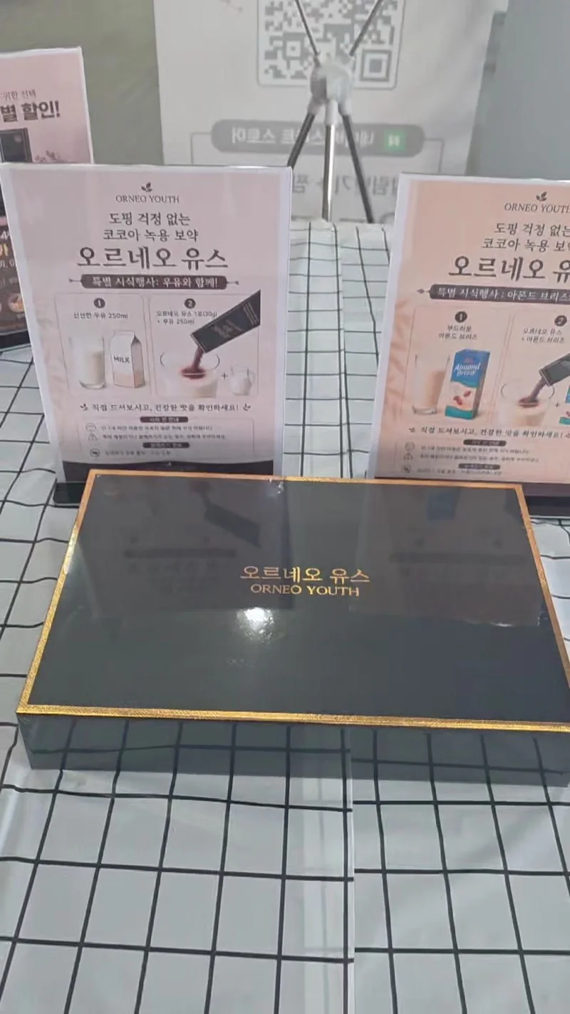 시식 부스에 놓인 오르네오 유스 블랙 골드 패키지와 우유 및 아몬드 음료 시식 안내